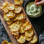 Homemade keto cottage cheese chips arranged on a wooden serving board with avocado dip