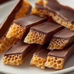 Keto honeycomb candy pieces in a glass jar, some chocolate-dipped